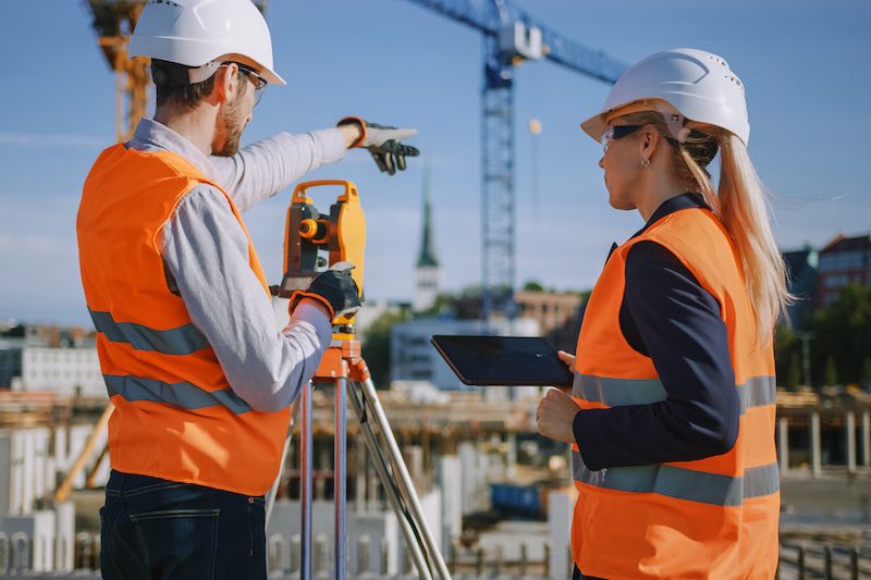 byggnadsarbetare som anvander teodolitmatning